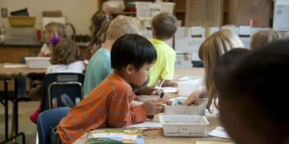 Students working on hands-on activities at a long table.