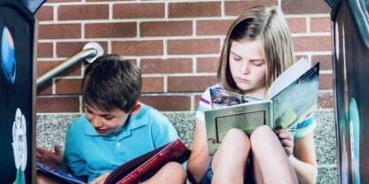Two kids reading together at the top of a slide.