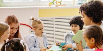 Two teachers working with a variety of kids at a round table.