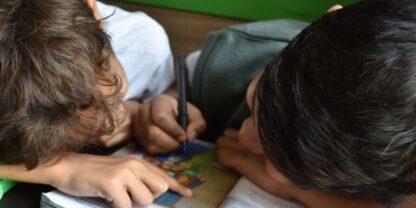 Two students writing in a book together while working on small group reading activities.