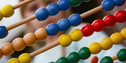 An abacus in the foreground representing one of many fractions activities, with a blurry human figure in the background.