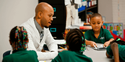 A teacher sitting around a table with several students.