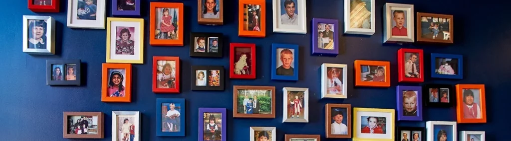 Dozens of framed photos hanging on a blue wall.