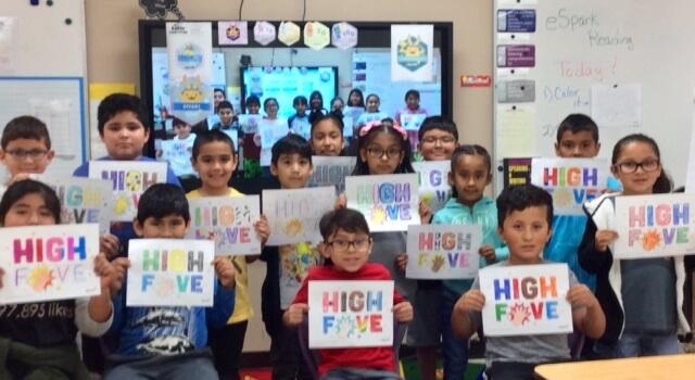 Students holding High Five coloring pages. 