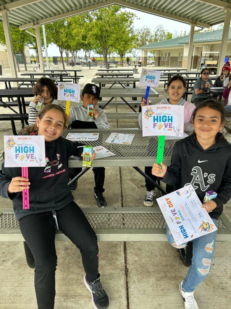 Students celebrating High Five Day, holding certificates.