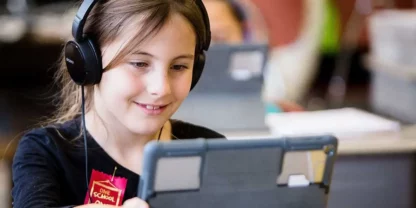 Ridley student looking at tablet with headphones on